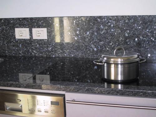 Nahaufnahme einer Küchenarbeitsplatte aus 'Labrador Blue Pearl' Granit, gekennzeichnet durch eine tiefblaue Grundfarbe mit auffälligen grauen und silbernen Schimmereffekten, die der Oberfläche ein elegantes und luxuriöses Aussehen verleihen.